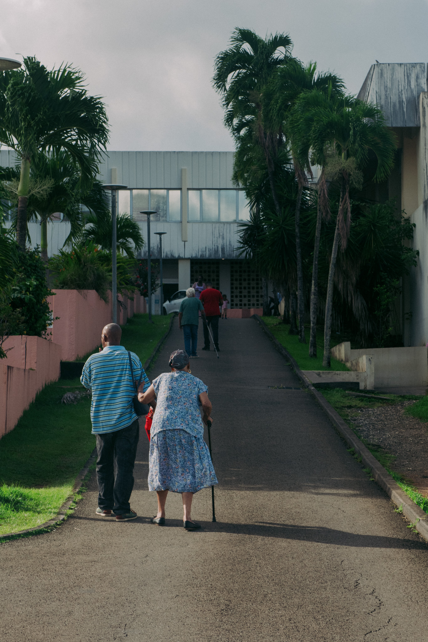 Un couple de dos se tenant par le bras qui marche vers un b&acirc;timent