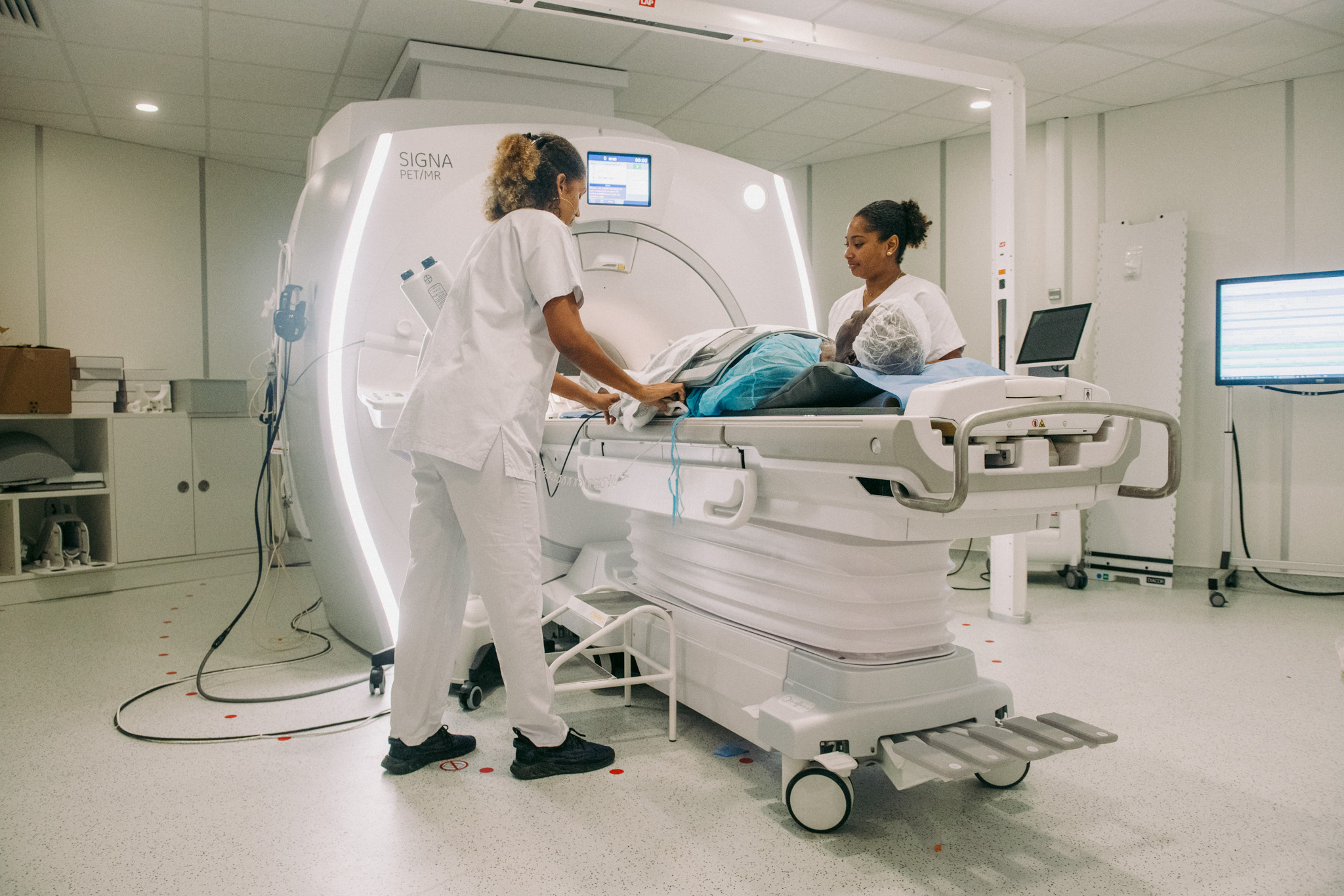 Deux soignantes accompagnant un patient allongé pour un examen d'imagerie nucléaire